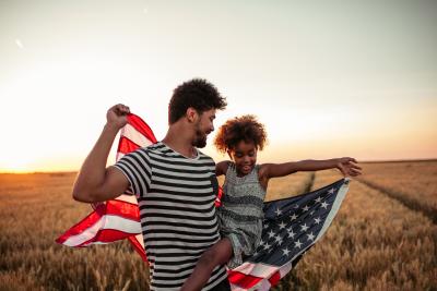 Photo of dad and child in a field with an American flage