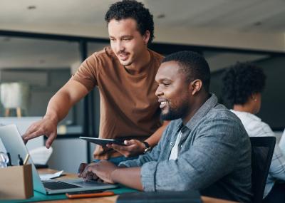 Two men at a desk working at a computer.