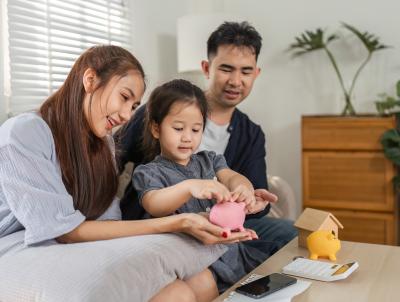 Mom and Dad with child putting cash in a piggy bank