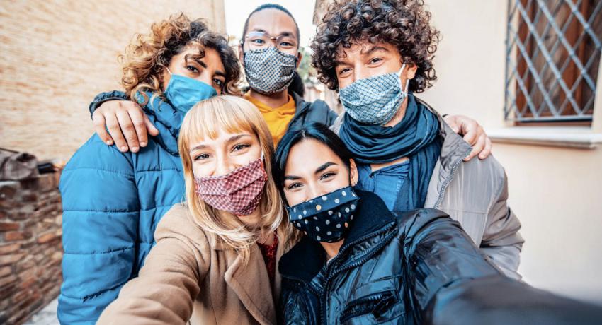 Youth wearing face masks gather for a selfie. 