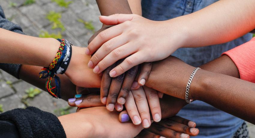Youth pile their hands together in unity. 