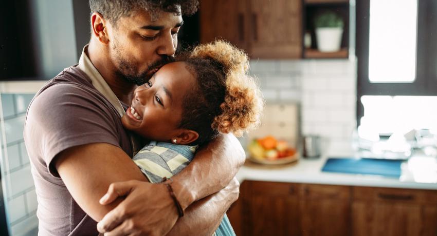 Young father hugging his daughter in the kitchen