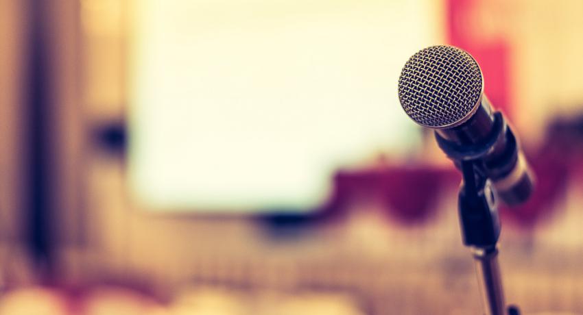 Image of a microphone with a blurred auditorium background. 