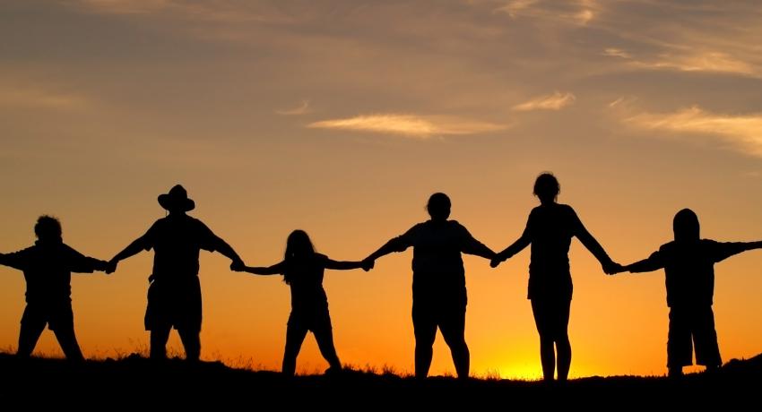 Community holding hands in sunset -- partnership