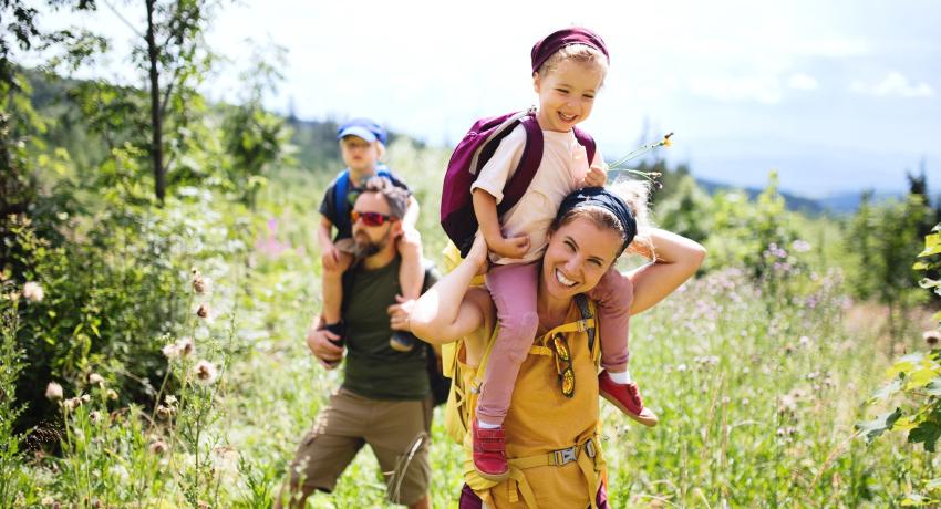 Family with small children hiking outdoors in summer nature