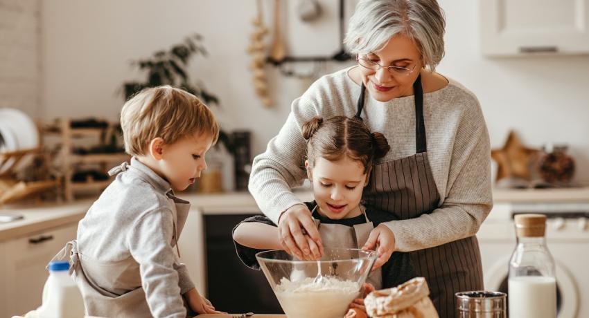 grandma cooking in the kitchen with two grandkids. 