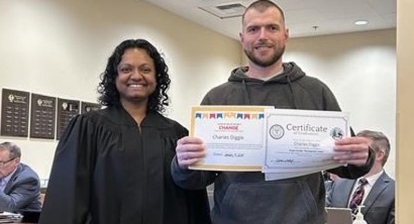 man standing next to judge with a certificate in his hand, both man and judge smiling