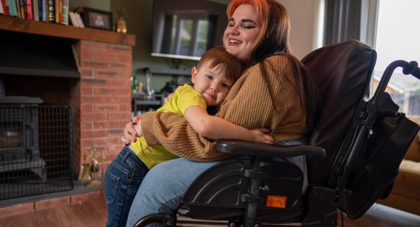 Woman in a wheelchair hugging a child