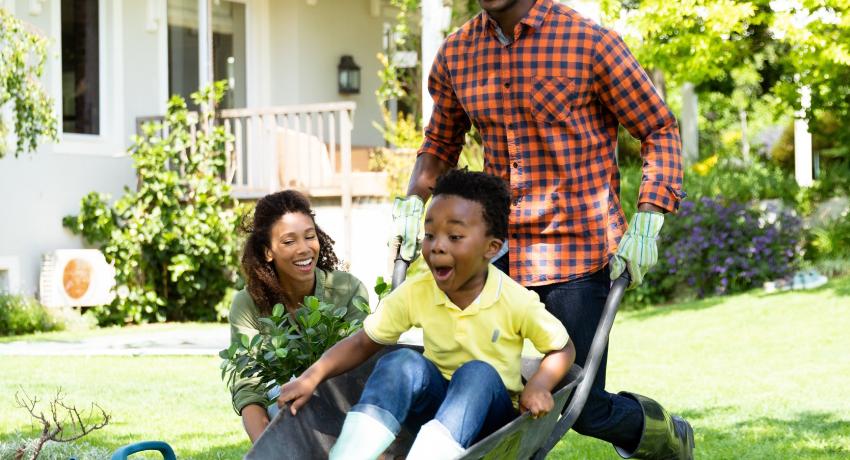 Adult pushing child in a wheel barrel